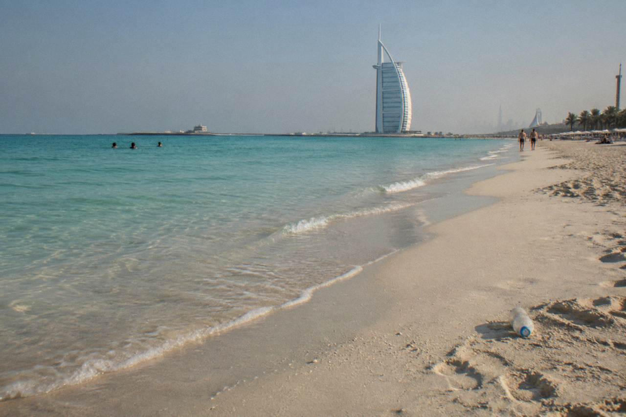 Wide sandy beach with calm shallow water and a clear sky
