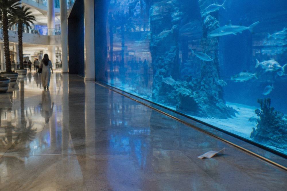 A shopping mall corridor with a large aquarium panel along one side