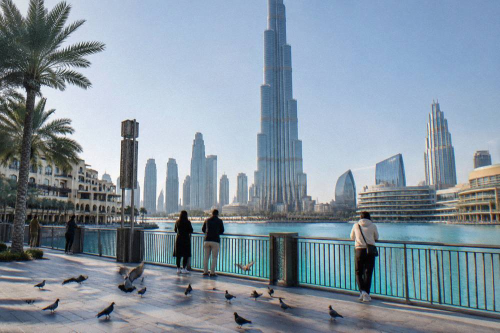 Visitors on the open waterfront promenade with the Burj Khalifa visible across the water