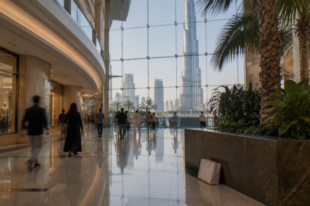 The wide interior corridor of the Dubai Mall with the Burj Khalifa visible through the glass frontage