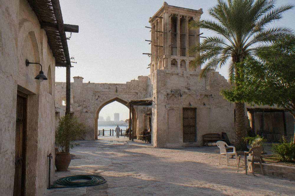 Courtyard of heritage style buildings with arched doorways and wind towers in Al Seef
