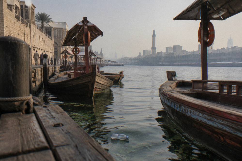 Wooden abra boats moored on Dubai Creek beside old district buildings