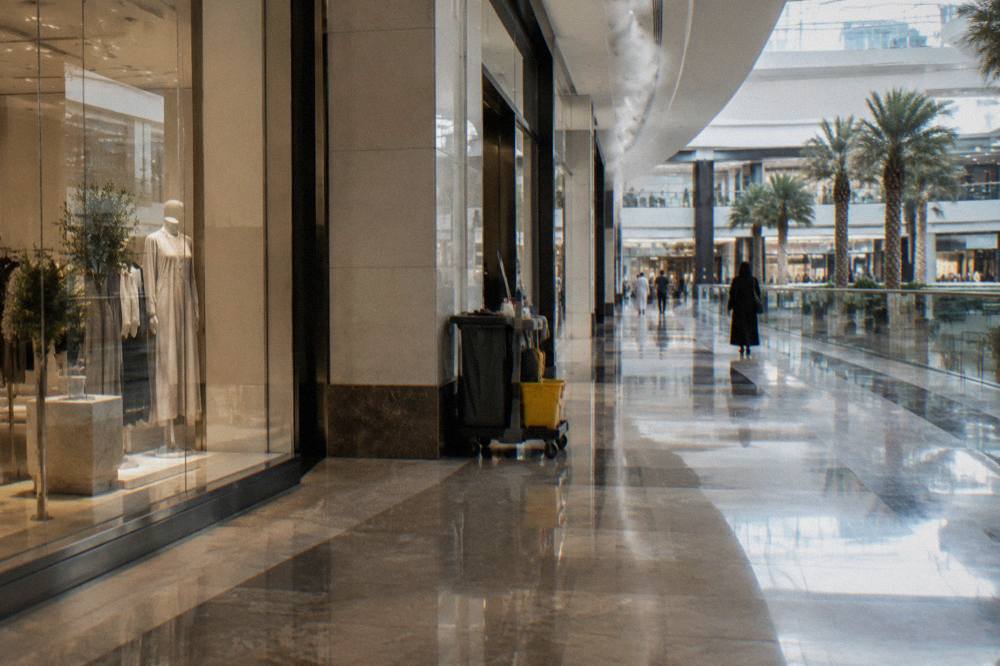 A wide mall corridor with polished floors and glass storefronts