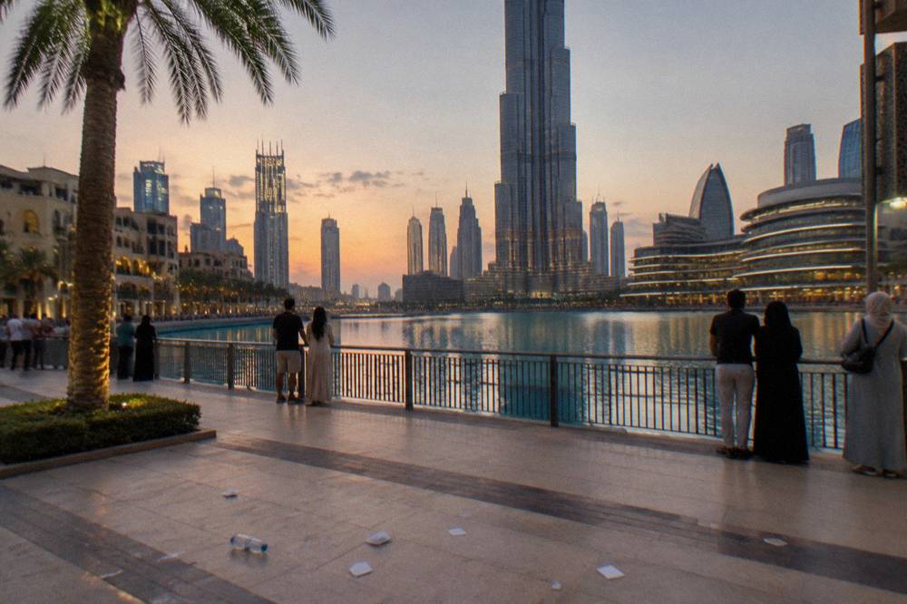 A lake waterfront promenade at dusk with a fountain area in the distance