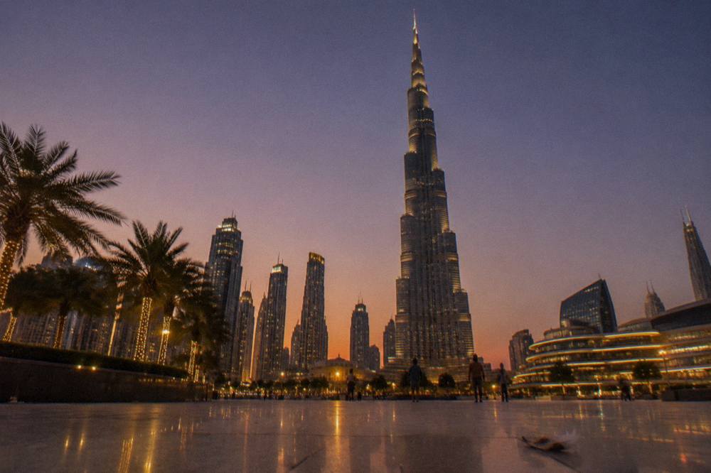 City skyline of Dubai at dusk with tall towers lit against the sky