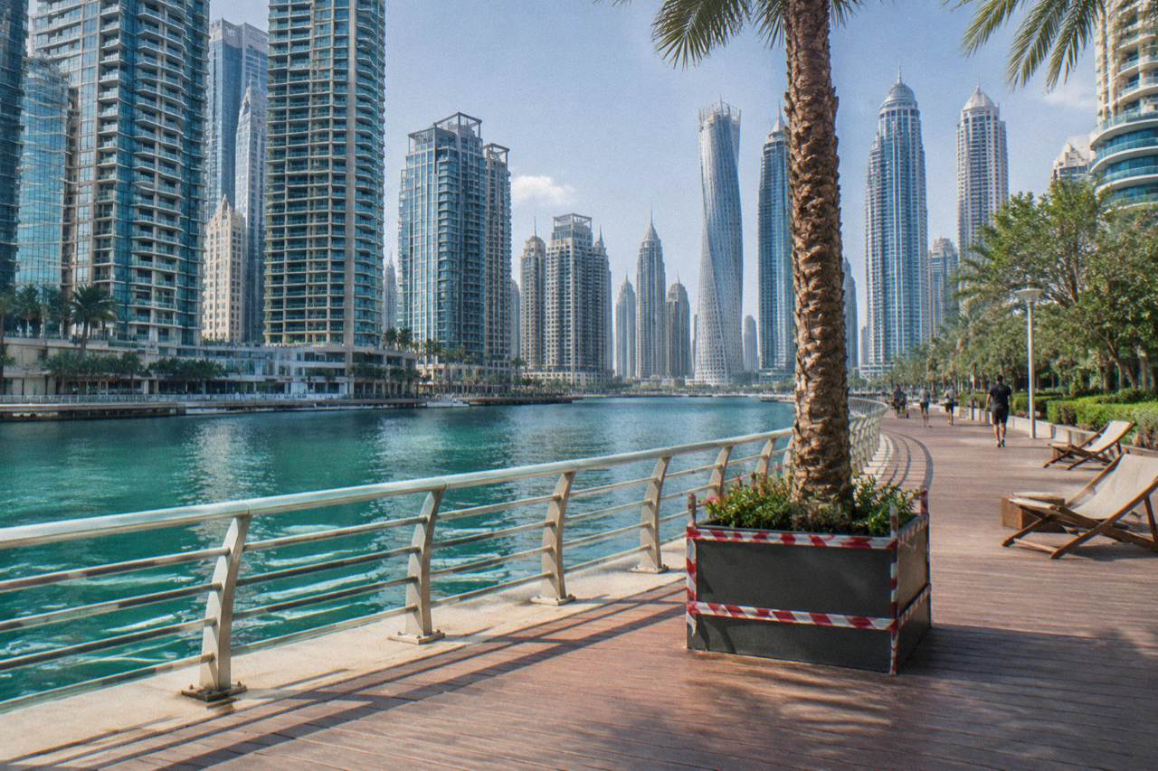 Open waterfront promenade in Dubai with modern towers along the water in daylight