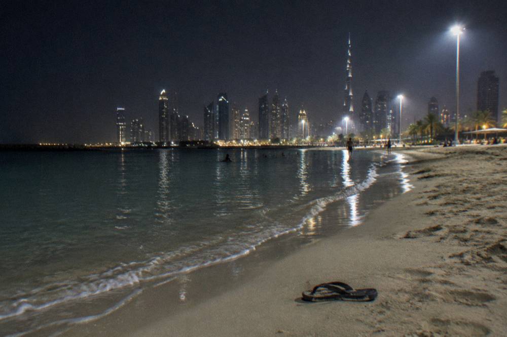 An illuminated public beach along the Dubai coastline at night