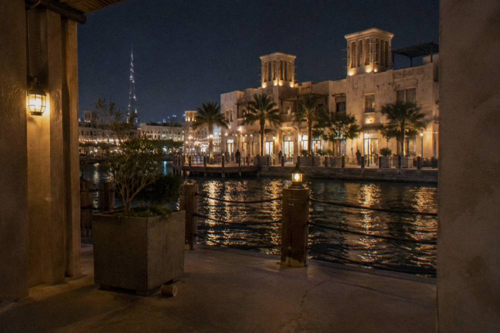 Illuminated shopfronts along a waterfront promenade in Dubai at night
