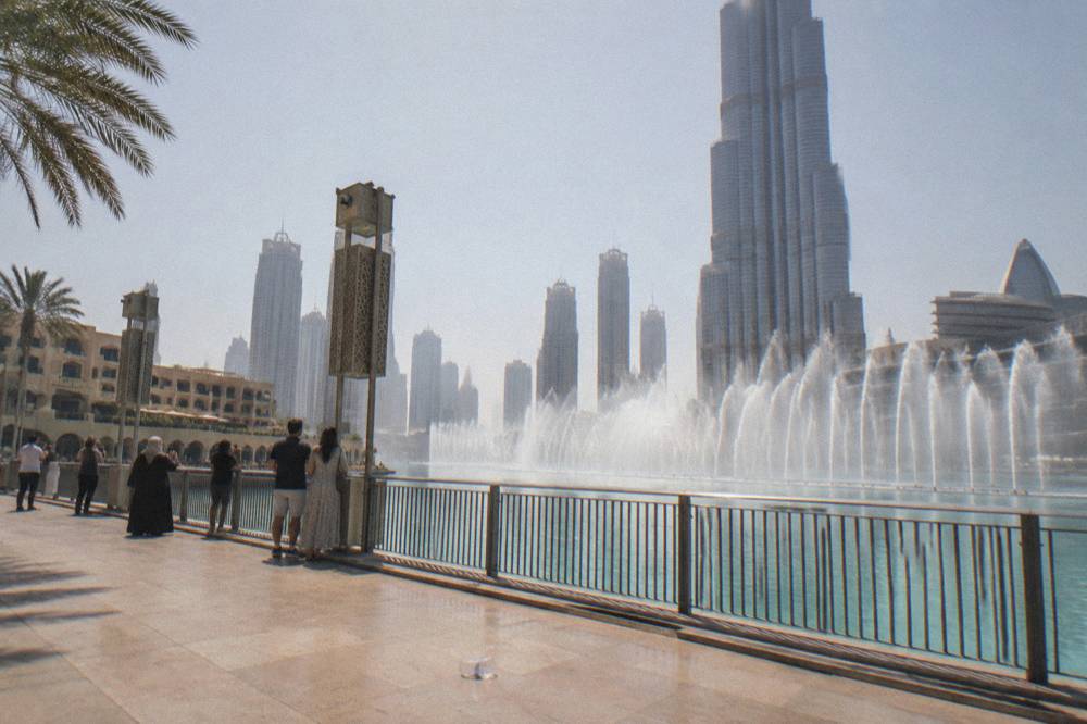 Fountain jets in daylight in front of a tall glass tower