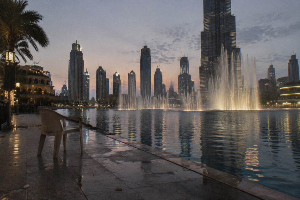 Crowd-free waterfront promenade beside a lake at dusk with city lights