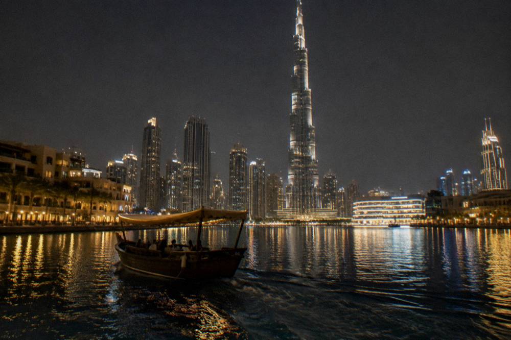 Boat on a city lake at night with illuminated buildings behind