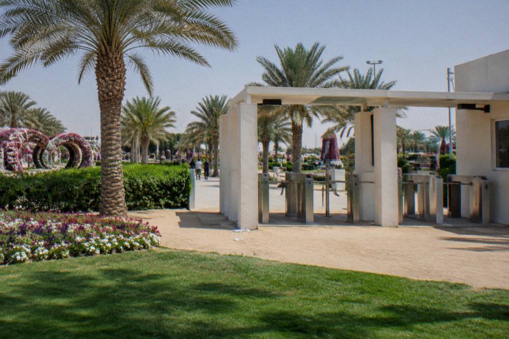 A park gateway with a ticket gate beside a landscaped lawn