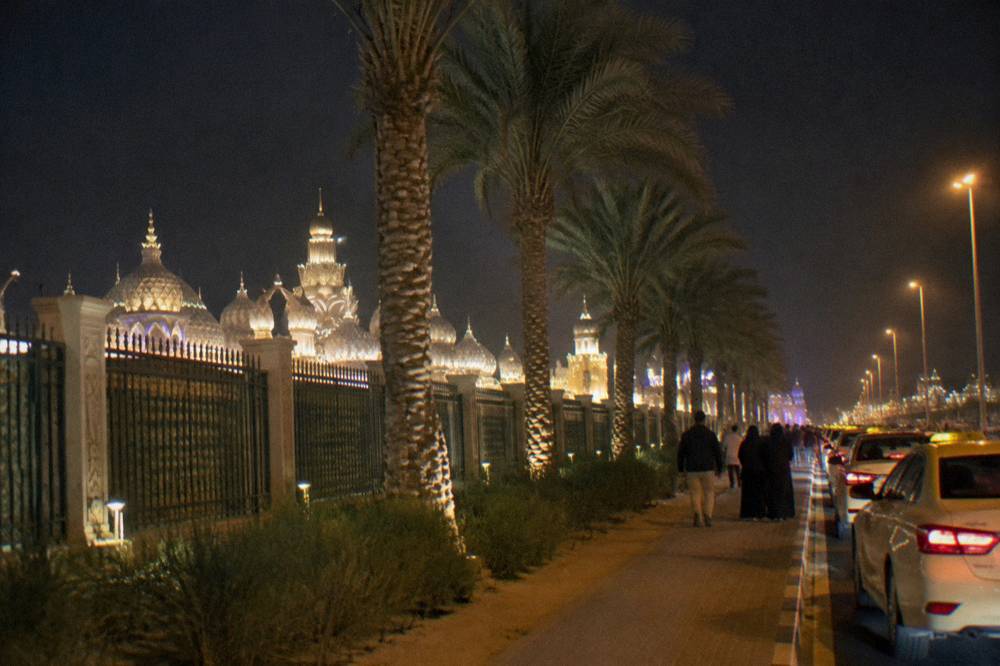 Evening crowds on a Global Village Dubai walkway between lit pavilions