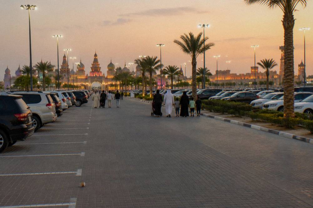 Global Village Dubai family visitors walking a lit promenade inside the park