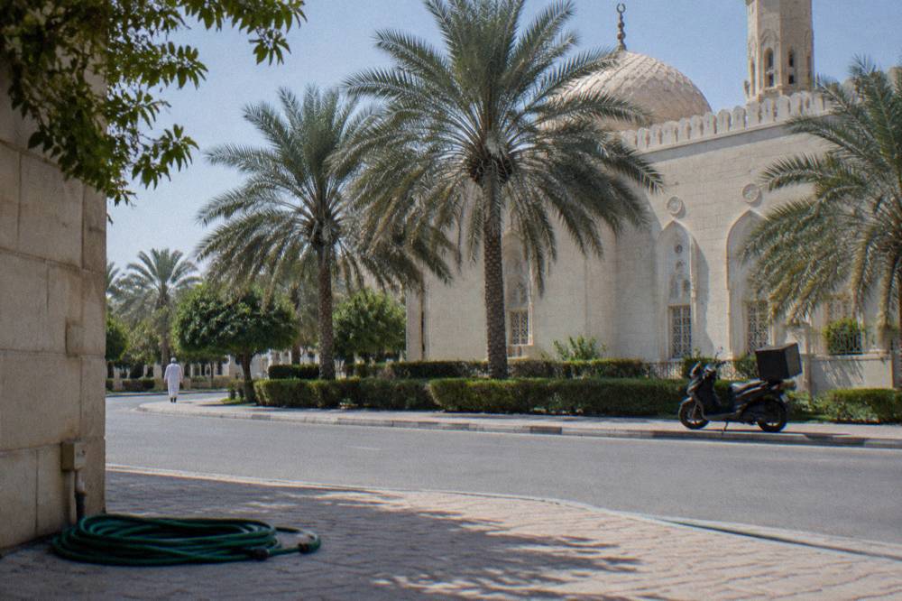 Courtyard of a white mosque with arched colonnades and a smooth stone floor