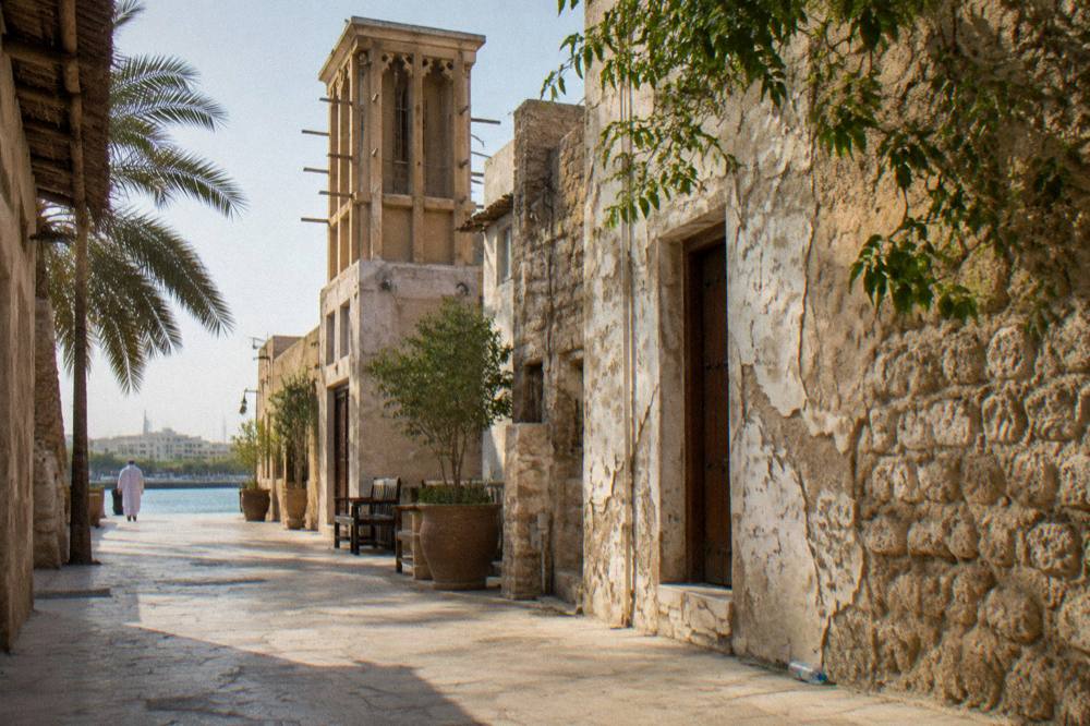 Wind tower rising above a row of old coral-stone houses in a heritage district