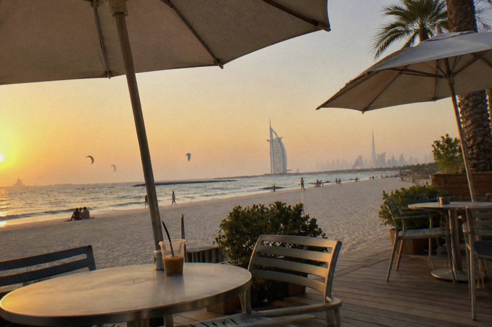 beachfront cafe terrace with tables and parasols along a promenade