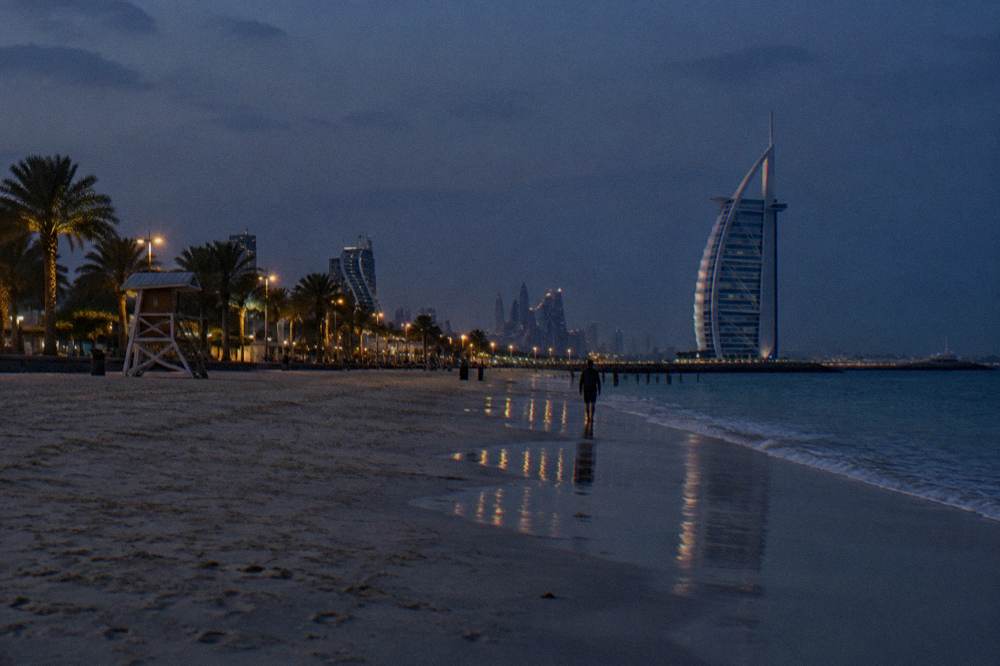 empty beach at dusk with lights beginning to show along a promenade