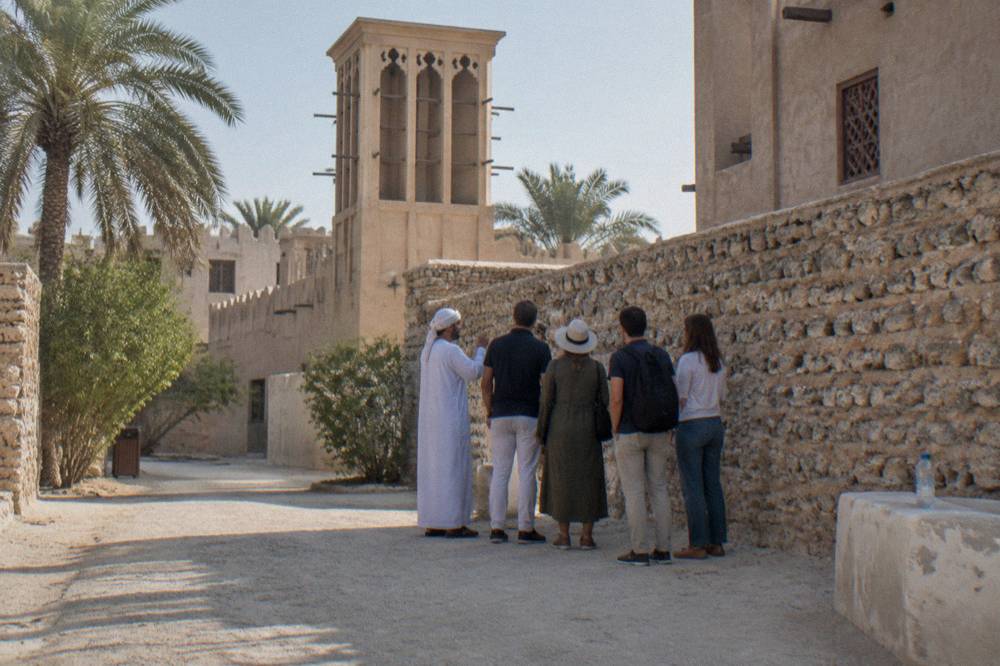 Guide speaking with a small group on a heritage street in Old Dubai