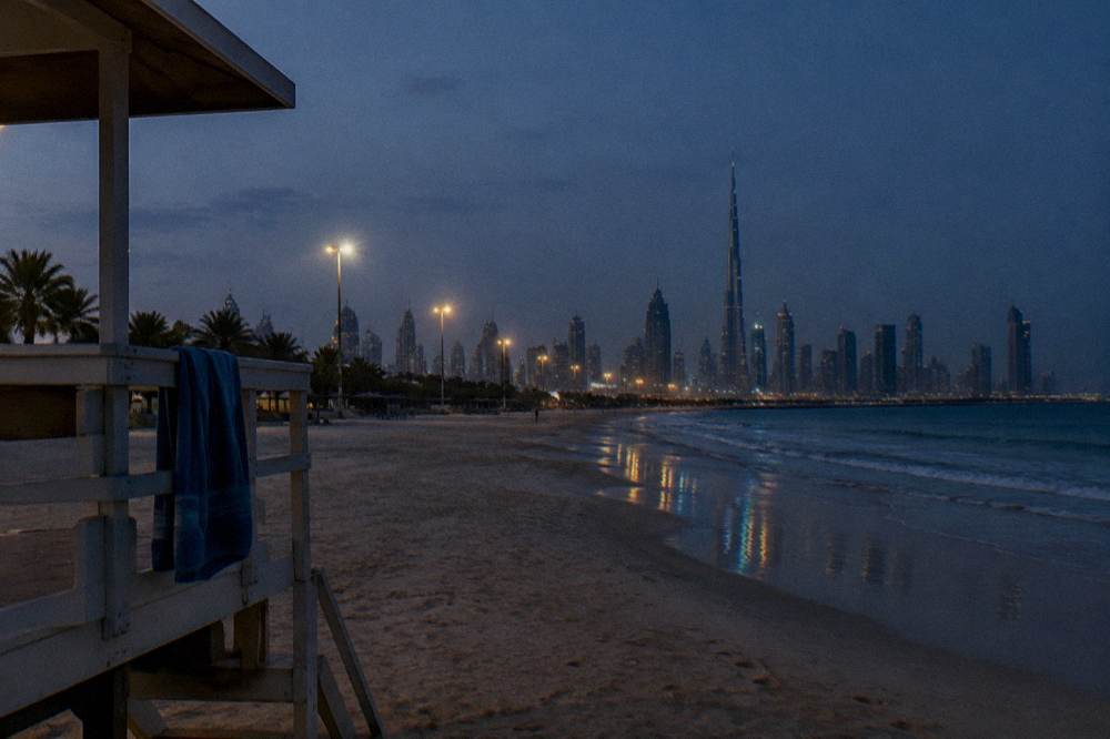 Beach at dusk with floodlights beginning to glow over the sand